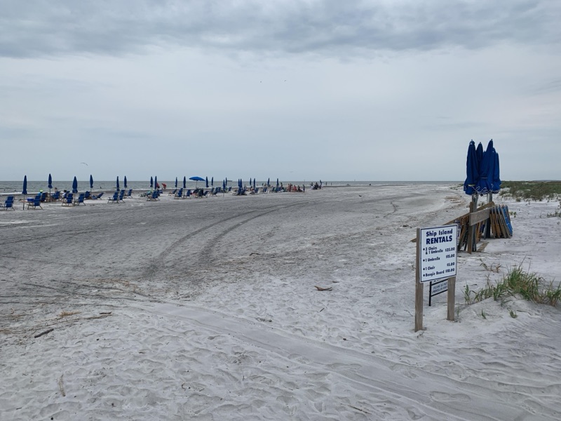 White sand, blue umbrellas and the water at Ship Island, Mississippi