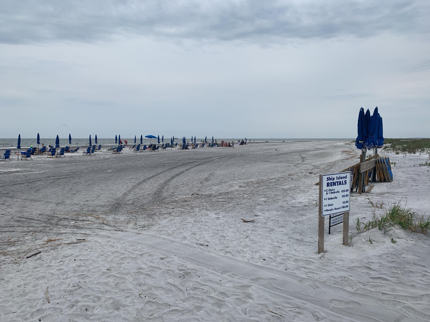 White sand, blue umbrellas and the water at Ship Island, Mississippi